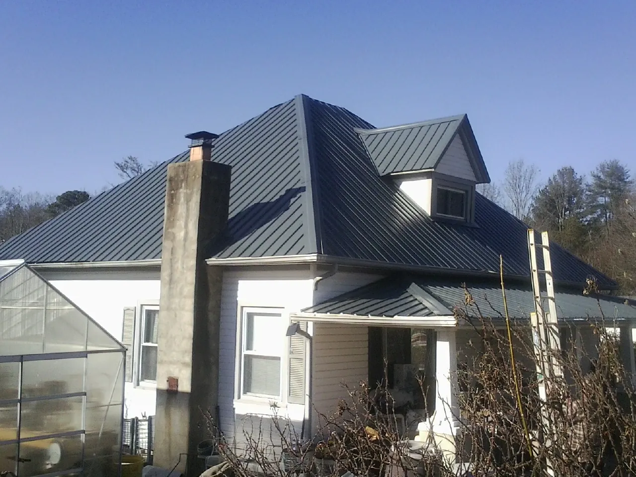Dark blue standing seam metal roof on a white farmhouse with dormer — Slate & Tile Roof Repair by Roofing Brothers in Pacoima