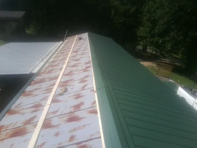 Old rusted panels beside newly installed green metal roofing — Wind Damage Roof Repair by Roofing Brothers in Pacoima