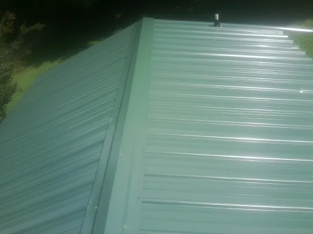 New green metal panels meeting at the ridge of a roof — Flat Roof Repair work by our crew in Pacoima