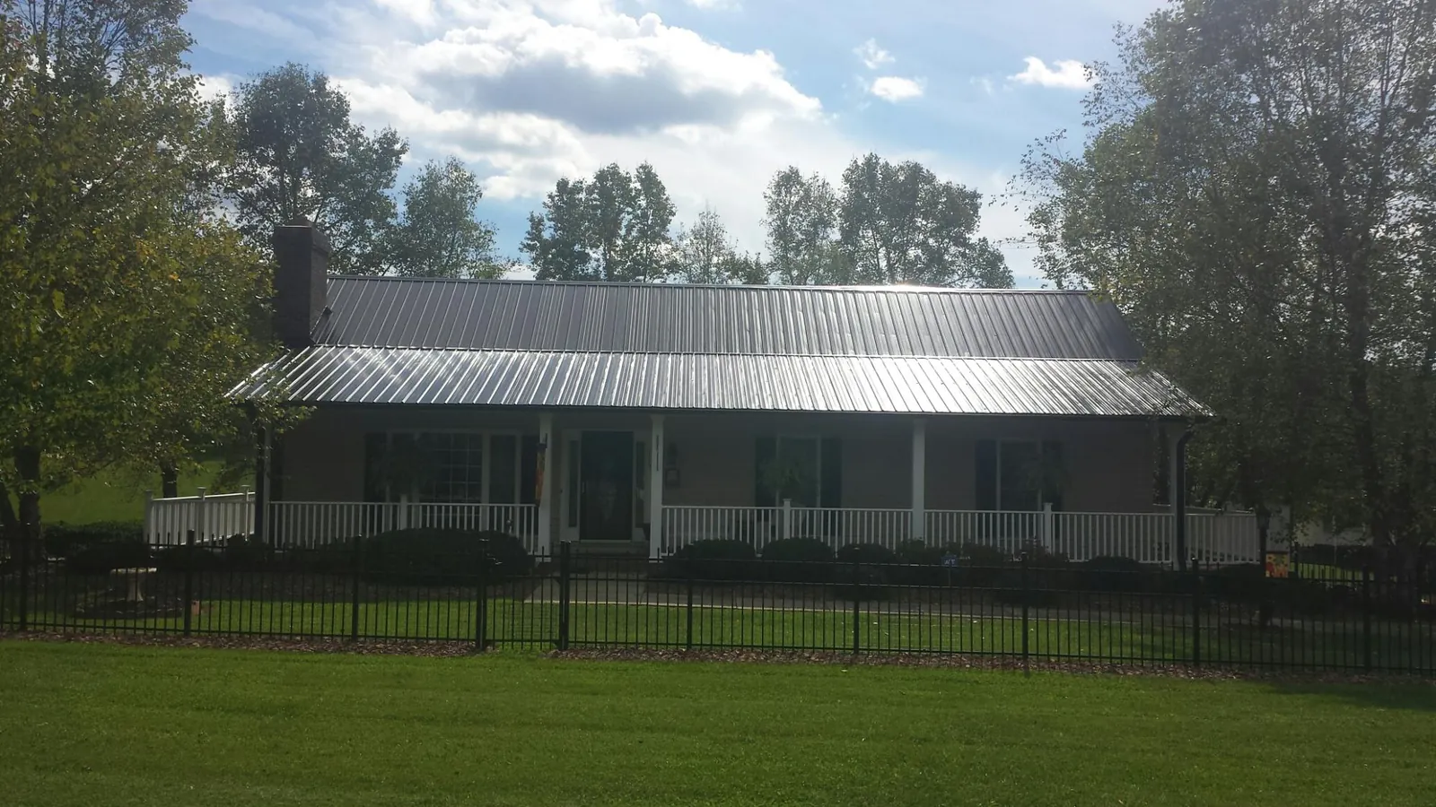 Gray metal roof on a brick ranch with a full width front porch — Gutter Guard Installation work by our crew in Pacoima